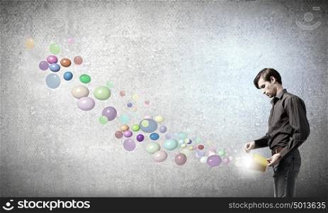 Add some color to your life!. Young man in casual splashing colorful balloons from bucket