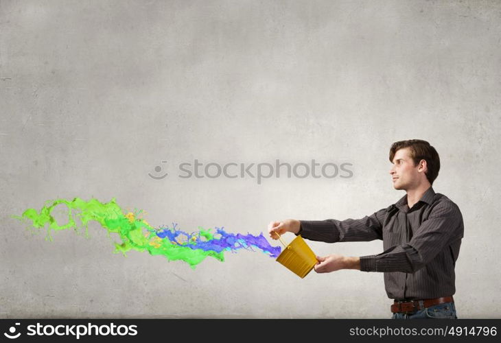 Add some color to your life!. Young man in casual splashing paint from bucket