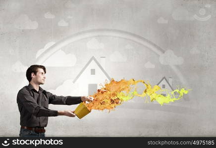 Add some color to your life!. Young man in casual splashing paint from bucket