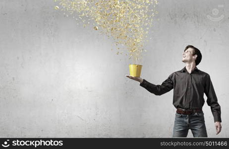 Add some color to your life!. Young man in casual splashing paint from bucket