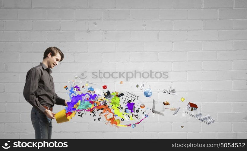 Add some color to your life!. Young man in casual splashing paint from bucket