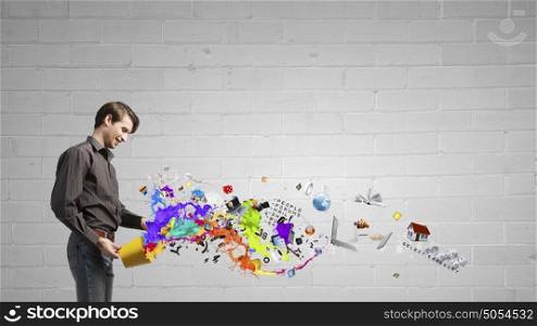 Add some color to your life!. Young man in casual splashing paint from bucket