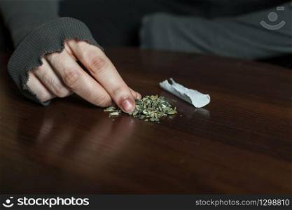Addict hands making marijuana jamb closeup, wooden background.. Addict hands making marijuana jamb closeup.