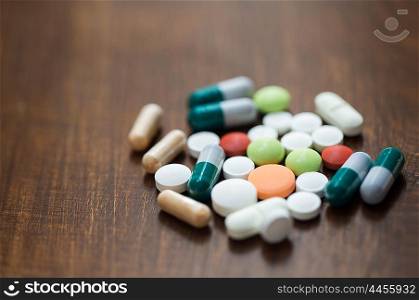 addiction, medication, medicine and substance abuse concept - close up of different drugs in pills and capsules on table