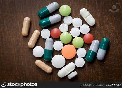 addiction, medication, medicine and substance abuse concept - close up of different drugs in pills and capsules on table