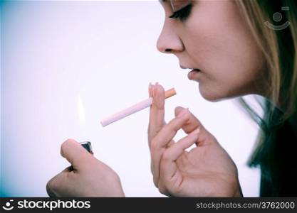 Addiction. Young woman with lighter lighting up cigarette. Addicted girl smoking. Nicotine problem. Copy space on white. Studio shot.