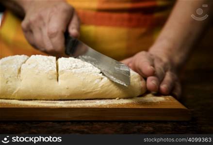 Adding cut to unbaked bread dough with serrated knife