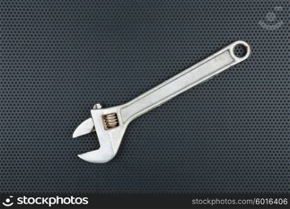 Adjustable wrench on a metallic background