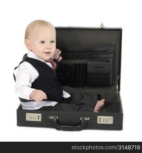 Adorable 10 month old baby boy in business suit, barefoot, sitting in empty briefcase.