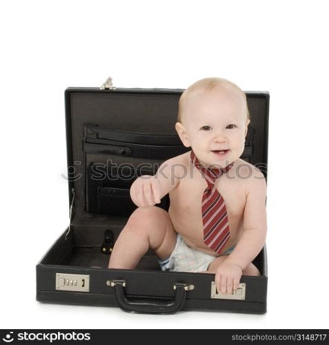 Adorable 10 month old baby boy in tie and diaper sitting in briefcase.
