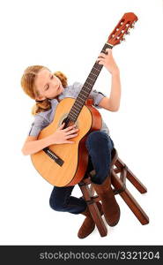 Adorable 7 year old blond girl playing acoustic guitar over white background.