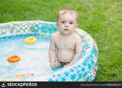 Adorable 9 months old baby boy sitting in the inflatable swimming pool??