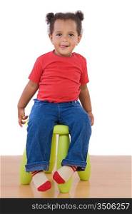 Adorable african baby sitting on green stool