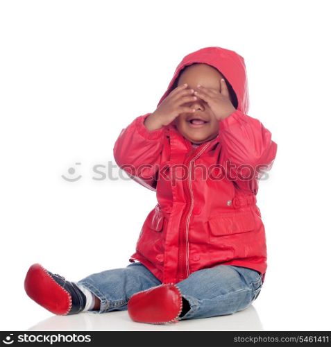 Adorable african baby sitting on the floor with red raincoat covering the face isolated on a white background