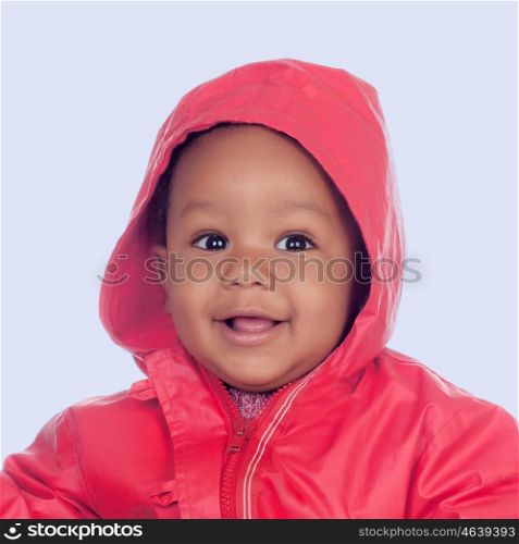 Adorable african baby with a beautiful smile and a red raincoat on a blue background