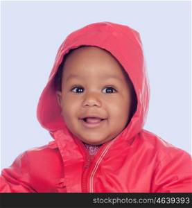 Adorable african baby with a beautiful smile and a red raincoat on a blue background