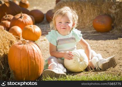 Adorable Baby Girl Holding a Pumpkin in a Rustic Ranch Setting at the Pumpkin Patch.