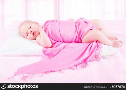 Adorable baby girl lying down in child's bedroom wrapped in beautiful pink blanket, carefree childhood, bedtime concept