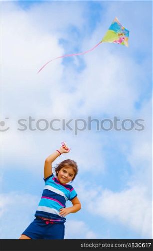 Adorable baby girl play with colorful kite outdoors, nice kid with toy on blue sky background, spending time in daycare, summer holidays concept