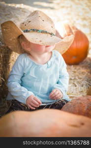 Adorable Baby Girl with Cowboy Hat in a Country Rustic Setting at the Pumpkin Patch.