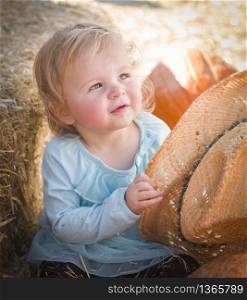 Adorable Baby Girl with Cowboy Hat in a Country Rustic Setting at the Pumpkin Patch.