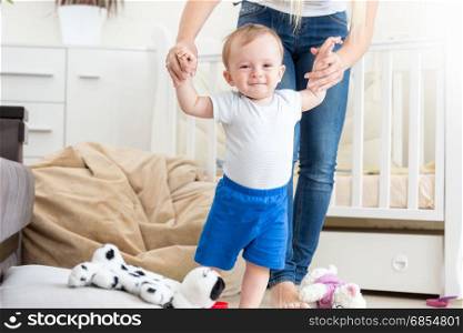Adorable baby learning how to walk with mother at home
