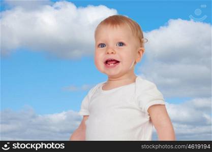 Adorable blond baby with two small teeth and a blue sky of background