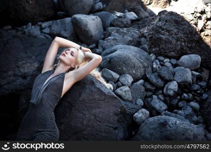 Adorable blond woman lying on the giant stones