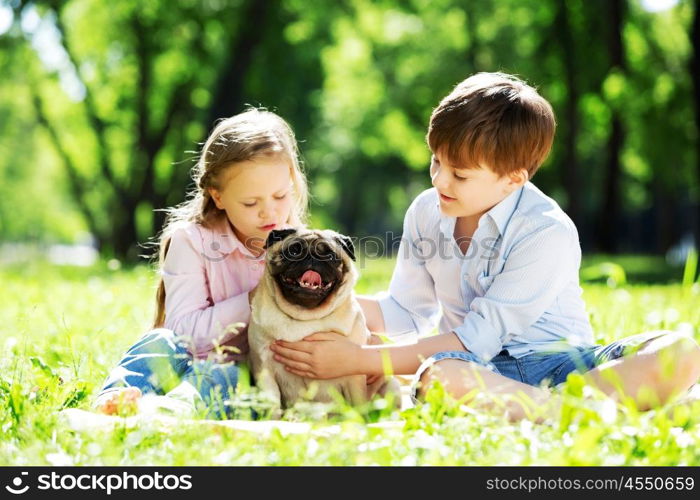 Adorable boy and girl in summer park with their dog. Summer weekend in park