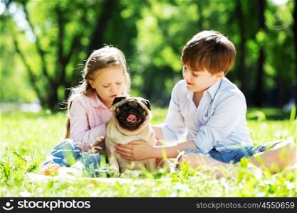 Adorable boy and girl in summer park with their dog. Summer weekend in park