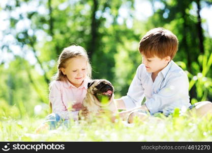 Adorable boy and girl in summer park with their dog. Summer weekend in park