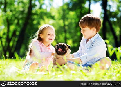 Adorable boy and girl in summer park with their dog. Summer weekend in park