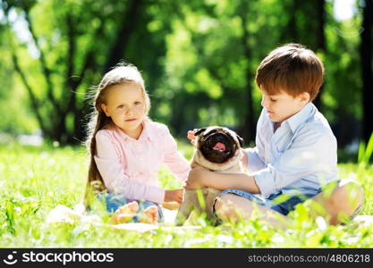 Adorable boy and girl in summer park with their dog. Summer weekend in park