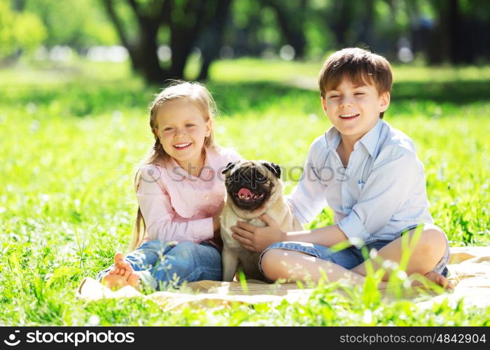 Adorable boy and girl in summer park with their dog. Summer weekend in park