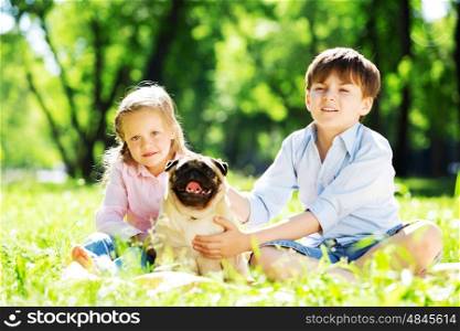 Adorable boy and girl in summer park with their dog. Summer weekend in park
