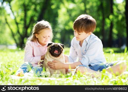 Adorable boy and girl in summer park with their dog. Summer weekend in park