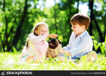 Adorable boy and girl in summer park with their dog. Summer weekend in park