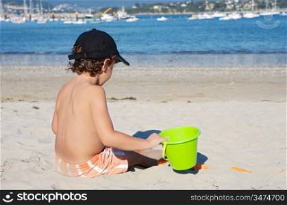 adorable boy playing in the beach with the sand
