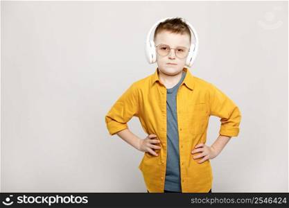 adorable child boy in white headphones and glasses isolated on grey background.. adorable child boy in white headphones and glasses isolated on grey background