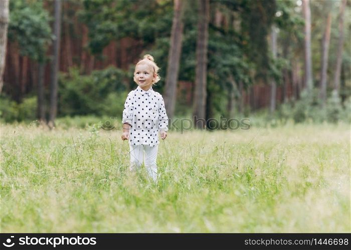 Adorable child, little toddler girl on a beautiful pine wood forest background. enjoying walking with family on a warm sunny day. selective focus.. Adorable child, little toddler girl on a beautiful pine wood forest background. enjoying walking with family on a warm sunny day. selective focus