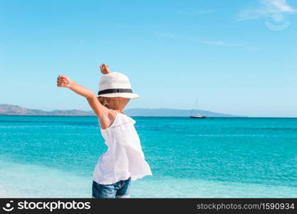 Adorable girl on the beach on background of the sea. Cute little girl at beach during summer vacation