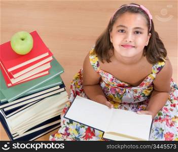 Adorable girl with many books reading