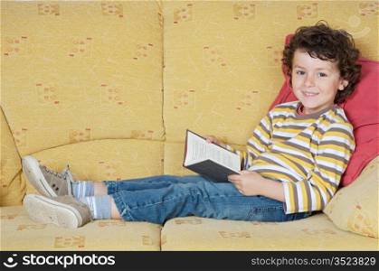 adorable happy boy reading in the armchair of your house