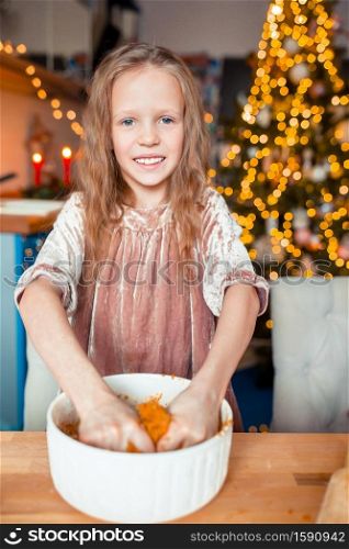 Adorable happy little girl baking Christmas gingerbread cookies at Xmas eve. Adorable little girl baking Christmas gingerbread cookies