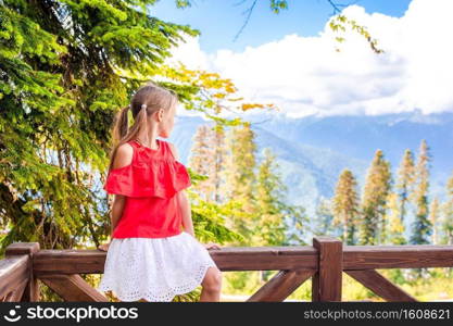 Adorable happy little girl in mountains in the background of beautful landscape. Beautiful happy little girl in mountains in the background of fog