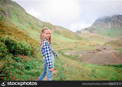 Adorable happy little girl in mountains in the background of beautful landscape. Beautiful happy little girl in mountains in the background of fog