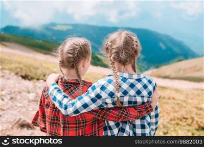 Adorable happy little girls in mountains in the background of beautful landscape. Beautiful happy little girls in mountains in the background of fog