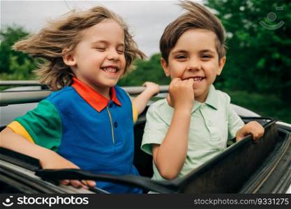 Adorable happy little kids stands in open car sunroof during road trip in countryside at summer. Concept of family leisure, active traveling. High quality photo. . Adorable happy little boys children in open car sunroof during road trip