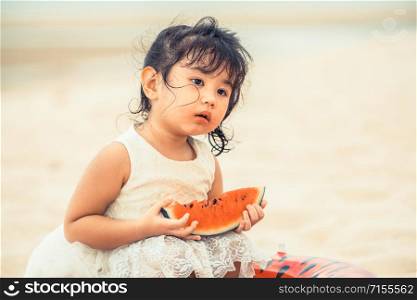 Adorable kid eating watermelon on the tropical sand beach in summer.. Adorable kid eating watermelon on the beach.