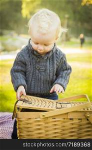 Adorable Little Blonde Baby Boy Opening a Picnic Basket Outdoors at the Park.
